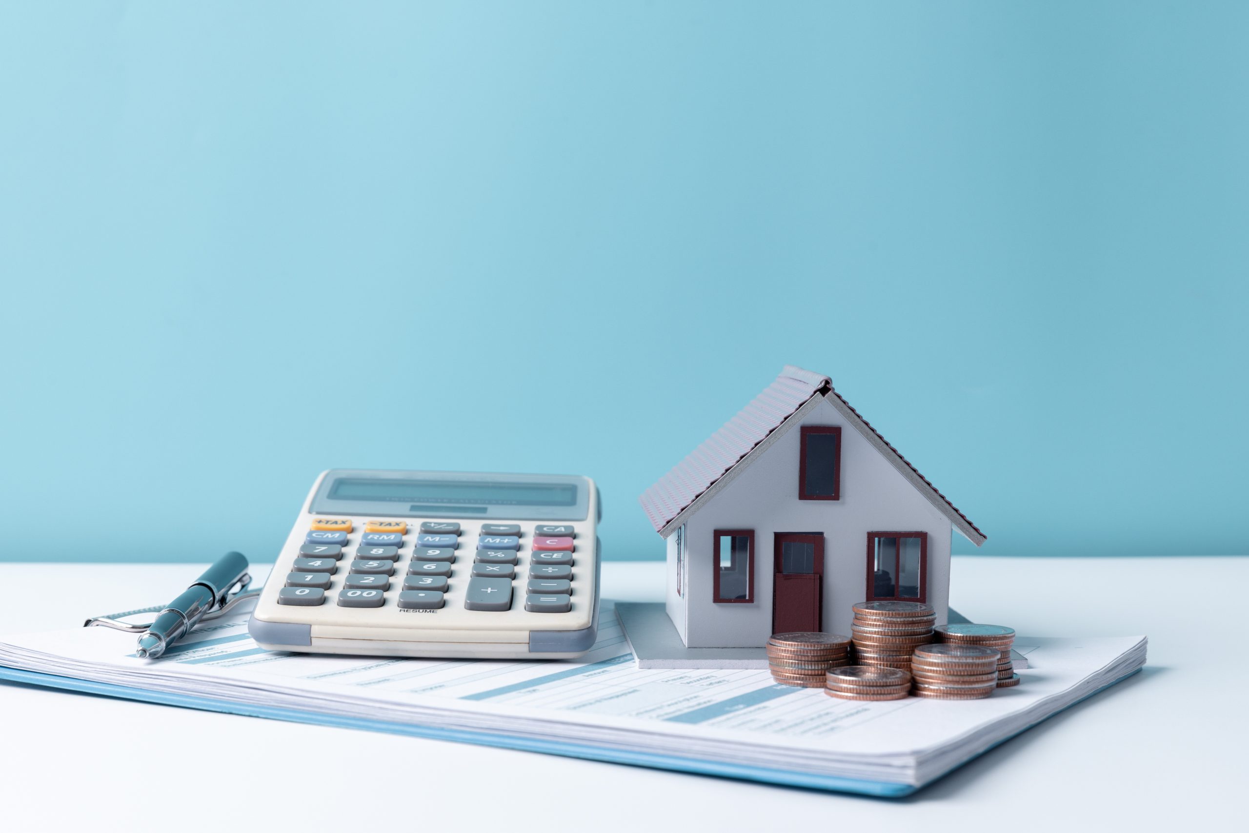 Taschenrechner und Modellhaus zur Berechnung von Kosten beim Hausverkauf